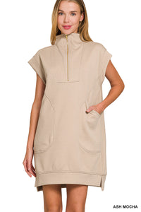 Woman wearing a beige sleeveless dress with a zipper on a white background