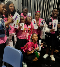 Load image into Gallery viewer, Group of children in pink shirts holding up cards with images of fashion dolls